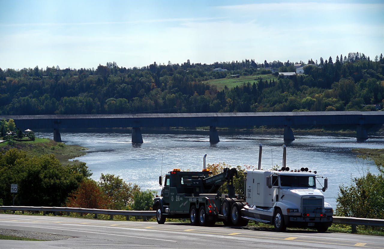 Tow truck on a roadside with the Hartland Covered Bridge in the background, New Brunswick.